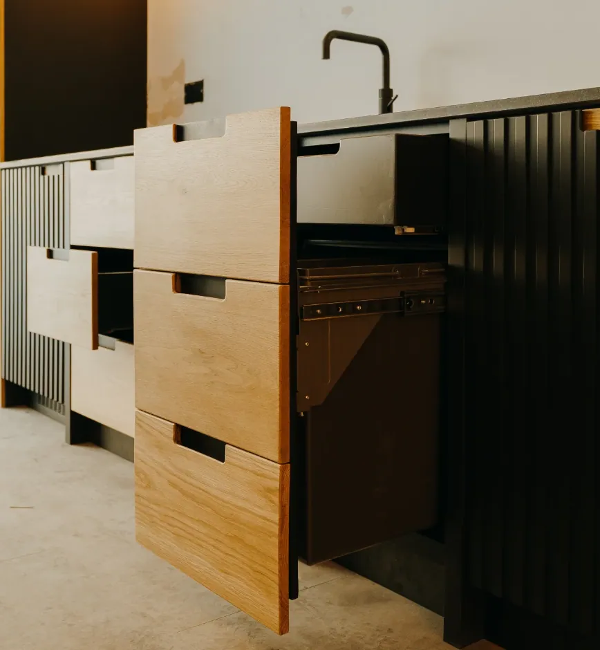 Stacked oak drawers with black cut-out handles and a pull-out waste bin