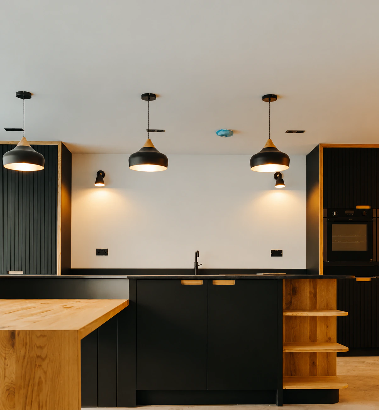 Warm minimalist kitchen with oak cabinetry and black units
