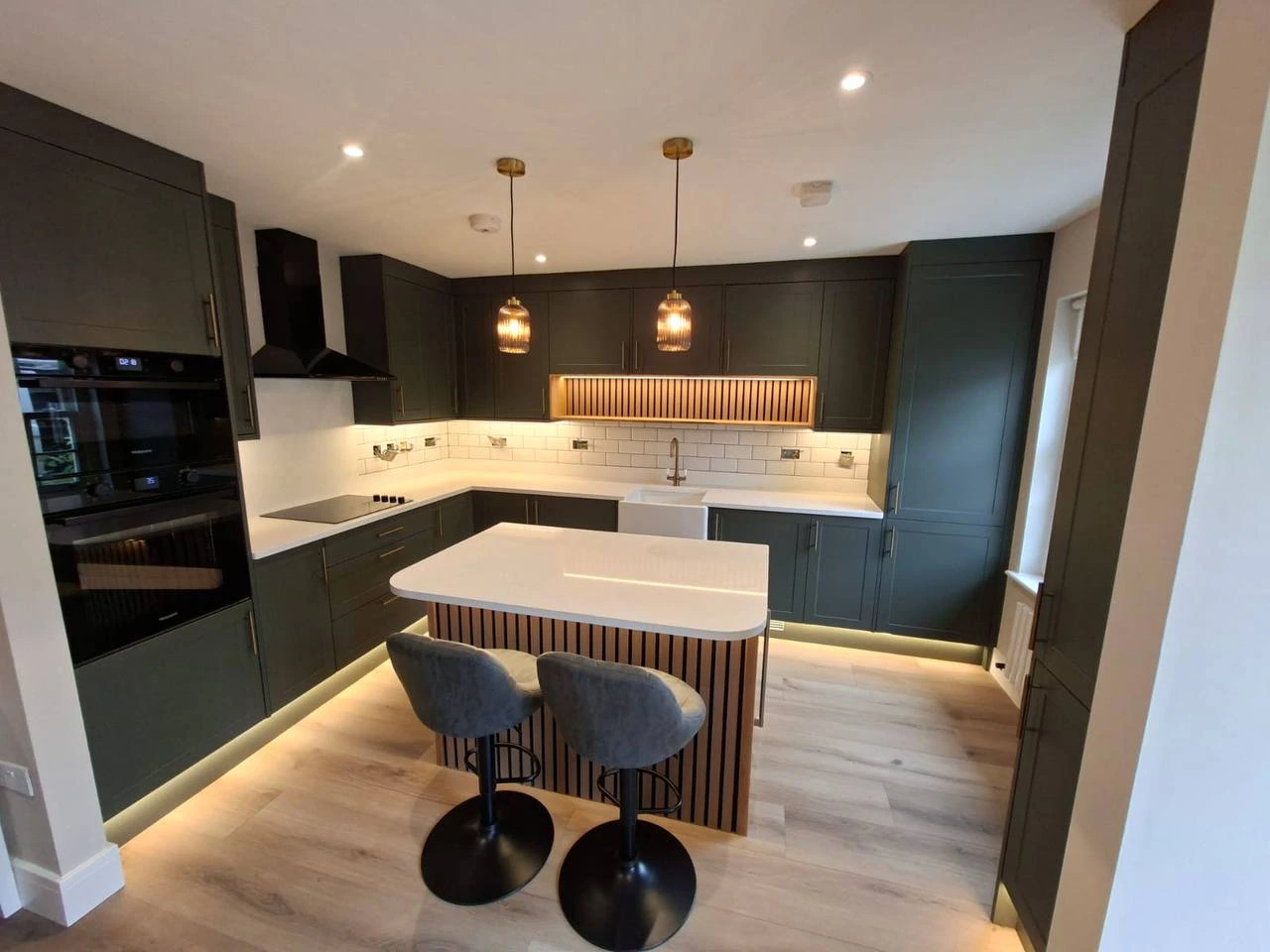 Oak drawers with cut-out handles pulled open beside black fluted panels