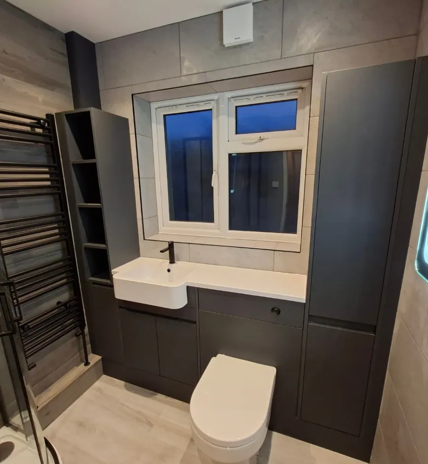 Matte black bathroom vanity with white basin, gold tap and grey stone tiles
